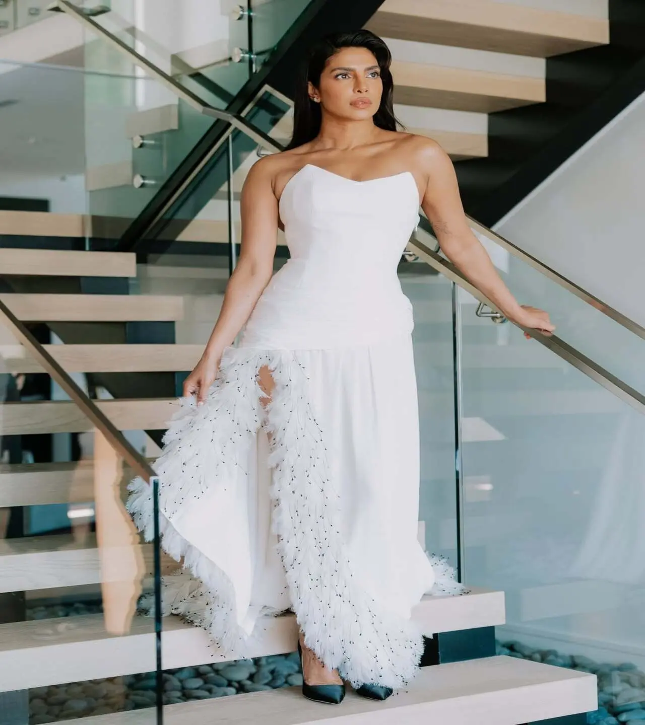 For the Oscars, Priyanka wore a strapless white Dior dress with draped detailing, a leg slit, and feathered trim, paired with a statement necklace and black pumps